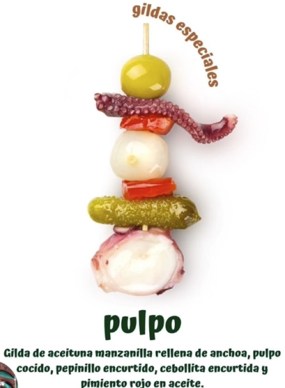 Cartel «gildas especiales · pulpo»: gilda de aceituna manzanilla rellena de anchoa, pulpo cocido, pepinillo encurtido, cebollita encurtida y pimiento rojo en aceite.