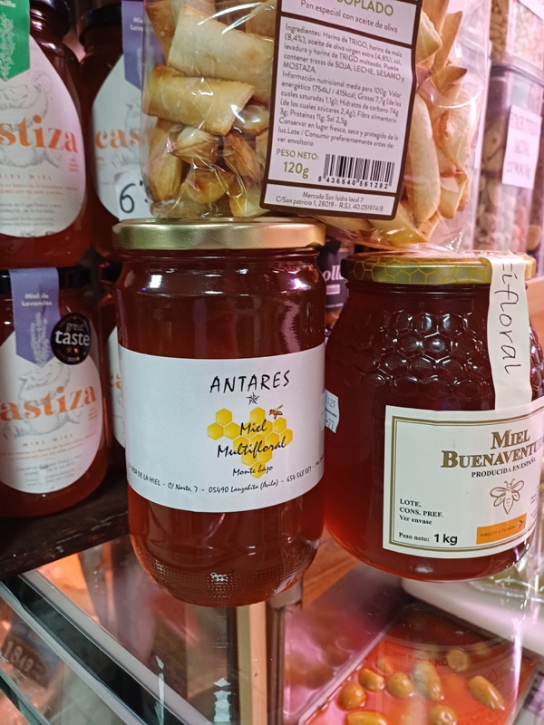 Tarros de miel artesana en el puesto: miel multifloral Antares y miel Buenaventura de un kilo.